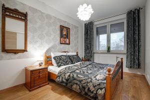 a bedroom with a bed and a nightstand and windows at Villa Garden Paryski in Olsztyn