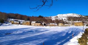 un campo cubierto de nieve con casas y una montaña en O Busto Aldea Rural, Apartamento HORNO 1, en Pobra do Brollón