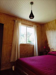 a bedroom with a purple bed and a window at cabañas aulen chepu chiloe in Ancud