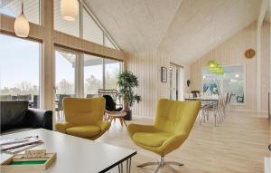 NørbyにあるBeautiful Home In Ringkbing With Sauna, Wifi And Outdoor Swimming Poolのリビングルーム(黄色い椅子、テーブル付)