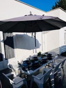 un tavolo e sedie sotto un ombrellone su un patio di 100m2 2 chambres 8 personnes - Grand parking et terrasse privée - Proche CDG-Parc expositions-Paris-Astérix-Disney a Villepinte