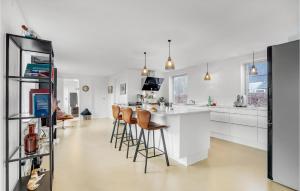 una cocina con armarios blancos y un bar con taburetes en Gorgeous Home In Sunds With Kitchen en Sunds