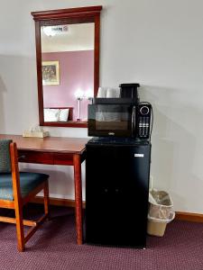 a microwave sitting on top of a refrigerator next to a table at Attica Inn in Attica