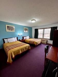 2 camas en una habitación de hotel con paredes azules en Attica Inn, en Attica