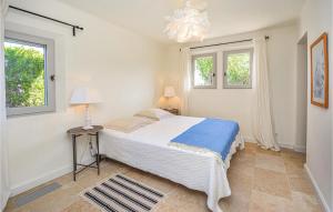 ein weißes Schlafzimmer mit einem Bett und zwei Fenstern in der Unterkunft L'amandier in Saint-Rémy-de-Provence