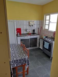 eine kleine Küche mit einem Tisch und einem Herd in der Unterkunft Casa Pôr do Sol in Itanhaém