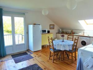 a kitchen with a table with chairs and a refrigerator at La Gicqueliere in Saint-Pair-sur-Mer