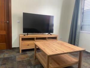 a flat screen tv on a wooden stand with a coffee table at Viv.Vacacion. Lucía: Apartamento céntrico Ingenio. in Ingenio