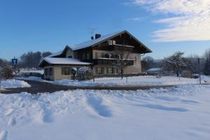 a house with snow on the ground and trees at Kurparkpension Stephan in Bad Endorf