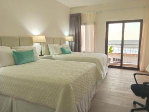 2 łóżka w pokoju hotelowym z widokiem na ocean w obiekcie Tramonto Boutique Hotel w mieście La Ceiba