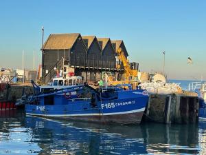 a blue boat is docked at a dock at Beautiful seaside Willow Cottage hosted by Whitstable-Holidays in Whitstable