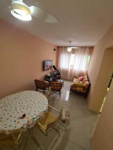 a dog standing in a living room with a table and chairs at Apartamento Praia Guarujá in Guarujá