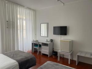 a bedroom with a bed and a desk and a tv at Hotel Ilha in Angra do Heroísmo