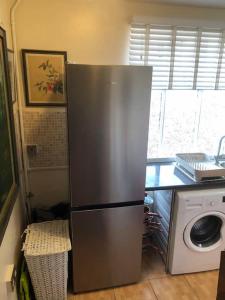 a stainless steel refrigerator in a kitchen with a washing machine at Charming 2 bedroom flat in Canterbury
