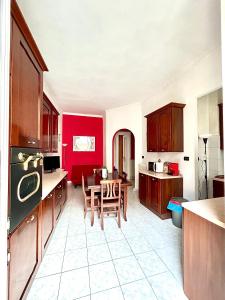 une cuisine avec des placards rouges et une table avec des chaises dans l'établissement Bella House, a 200 metri dalla metropolitana, à Turin