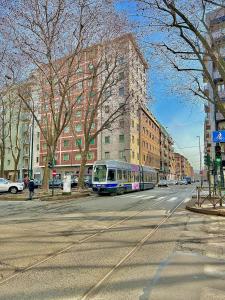 un train circulant dans une rue de la ville avec des bâtiments dans l'établissement Bella House, a 200 metri dalla metropolitana, à Turin