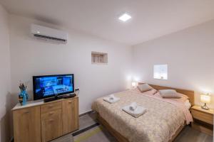 a bedroom with a bed and a flat screen tv at Bozena's studio apartment in Split