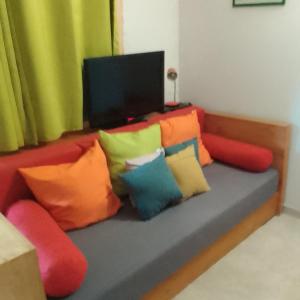 un sofá con almohadas coloridas y TV en KAZA CHARLY F2, en Les Abymes
