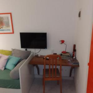 Habitación con escritorio, TV y sofá. en KAZA CHARLY STUDIO en Les Abymes