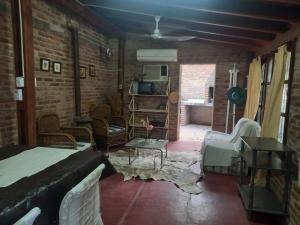 uma sala de estar com uma cama e uma parede de tijolos em El quincho em Las Padercitas