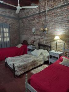 a bedroom with two beds and a brick wall at El quincho in Las Padercitas