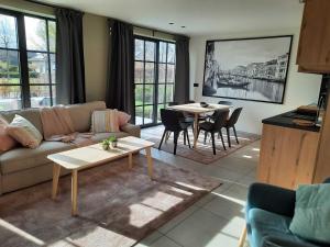 - un salon avec un canapé, des tables et des fenêtres dans l'établissement Tranquil villa in Vlaanderen with terrace, 