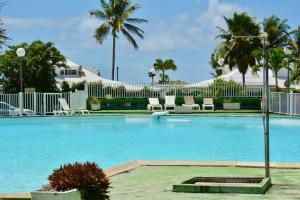 a swimming pool at a resort with palm trees at OCEANE 2 in Le Gosier