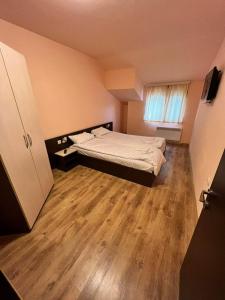 1 dormitorio con 1 cama y suelo de madera en Апартамент Lake, en Tryavna