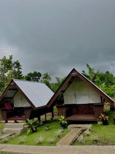 ein Haus mit Metalldach und Gras in der Unterkunft ROCA'S HOMESTAY Backpackers Chalet Bohol in Batuan