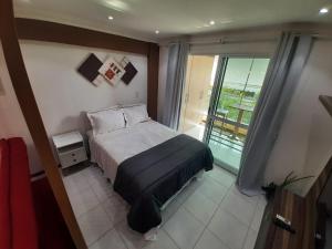 1 dormitorio con cama y ventana grande en Camboinhas LOFT Temporada en Niterói