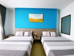 two beds in a hotel room with a blue wall at HÀO PHÁT HOTEL NHA TRANG in Nha Trang