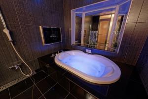 baño con bañera y espejo grande en ホテルパシオンリゾート, en Matsuyama