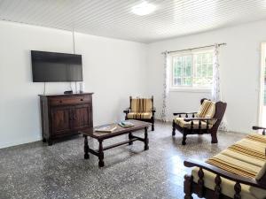 un soggiorno con TV, tavolo e sedie di Traditional Aruban Home close to Surfside Beach a Oranjestad