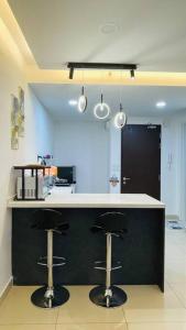 a kitchen with two bar stools at a counter at D'puncak Trefoil Setia Alam in Setia Alam