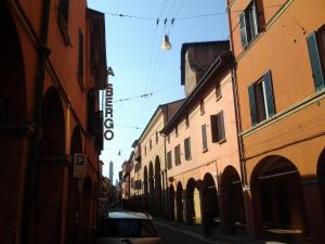 博洛尼亚佩拉酒店的两栋建筑之间的街道上停泊的汽车