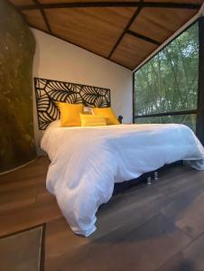 1 dormitorio con 1 cama grande con almohadas amarillas en Amanatu Ecolodge & Spa en Quimbaya