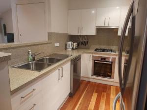 a kitchen with white cabinets and a stainless steel sink at Allawah at Smiths Lake in Smiths Lake