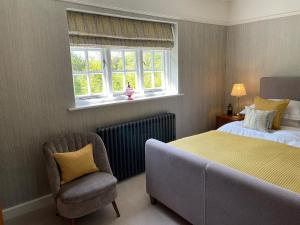a bedroom with a bed and a chair and a window at Banksiae in Tackley
