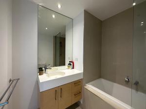 uma casa de banho com um lavatório, uma banheira e um espelho. em Prima Tower Apartment Face to Crown by GoodLive em Melbourne