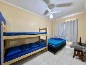 two bunk beds in a room with a ceiling fan at Cantinho do Churrasco - Varanda Gourmet a 60 mts praia in Praia Grande