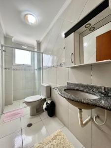 a white bathroom with a sink and a toilet at Cantinho do Churrasco - Varanda Gourmet a 60 mts praia in Praia Grande