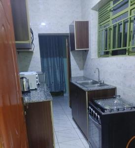 a small kitchen with a sink and a stove at Cozy & Private 1 Bedroom self contained Kigali-Kanombe in Kigali