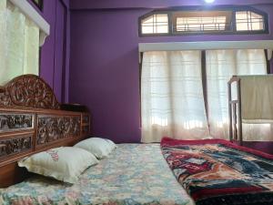 1 dormitorio con paredes moradas y 1 cama con 2 almohadas en Odyssey Stays Aalo, en Along