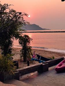 空望的住宿－Sea Sand House Resort，日落时坐在海滩吊床上的女人