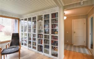 uma estante de livros com livros e uma cadeira num quarto em Gorgeous Home In Kpmannebro With Wifi em Köpmannebro