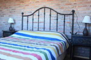 a bed with a colorful striped blanket and two lamps at Praia - Proa al Mar in Maldonado