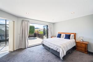 a bedroom with a bed and a sliding glass door at IRONSIDE LAKEVIEW TOWNHOUSE in Wanaka