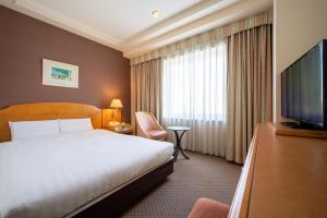 a hotel room with a bed and a flat screen tv at Hotel JAL City Aomori in Aomori