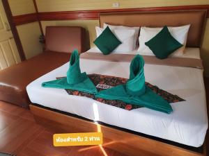 Una cama con dos toallas verdes. en The Royal Bamboo Lodges - SHA Certified en Khao Sok