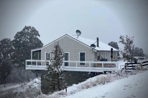 una casa cubierta de nieve con porche en Shiki Snow Cabin, en Cobungra